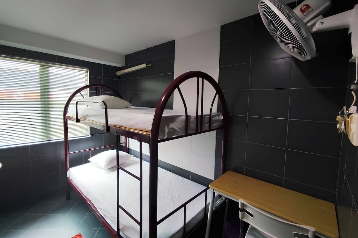 A bunk bed room with a desk and a hairdryer on the wall.