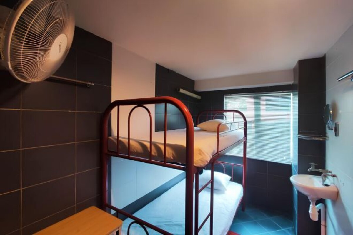 A bunk bed room with a fan, a sink, and a window with blinds.