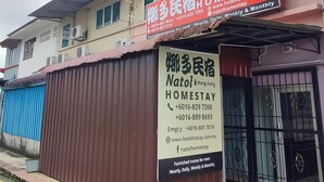 A two-story building with a red and white sign advertising a homestay service. - Natol Budget Homestay Rock Road (Kuching)