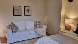 A cozy bedroom with a white sofa, two beds, a rug, and a wall clock. - Stockholm City Chic-1-Bedroom Loft for 3 (Stockholm)