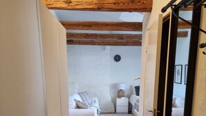 A narrow hallway leading to a bedroom with a bed, bedside table, lamp, and a clock on the wall. - Stockholm City Chic-1-Bedroom Loft for 3 (Stockholm)