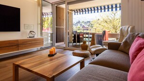 Een moderne woonkamer met een houten salontafel, een bank en een aan de muur bevestigde televisie.