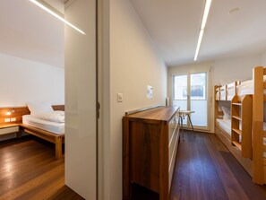 Ett modernt hotellrum med ett skrivbord i trä, en säng, ett litet bord och en våningssäng.