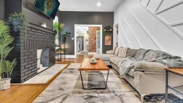 A modern living room with a fireplace, a sofa, a coffee table, and a TV mounted on the wall. - Serenity House | 2BR | 7 Min to Downtown ATL | Large Patio (Atlanta)