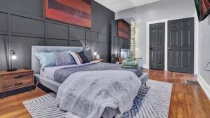 A modern bedroom with a large bed, a nightstand, a bedside lamp, and a mirror. - Serenity House | 2BR | 7 Min to Downtown ATL | Large Patio (Atlanta)