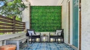 A small patio with a green wall, two chairs, a table, and a tiled floor. - Serenity House | 2BR | 7 Min to Downtown ATL | Large Patio (Atlanta)