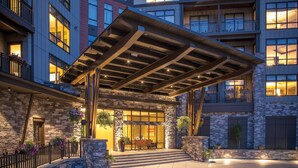 A hotel entrance with a covered patio, stone facade, and outdoor seating area.