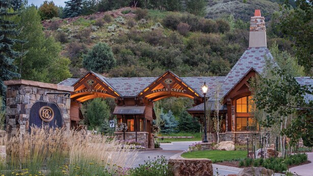 A lodge with a stone facade, wooden entrance, and a view of a mountainous landscape.