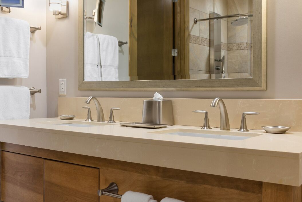 A modern bathroom with a large mirror, two sinks, and a shower.