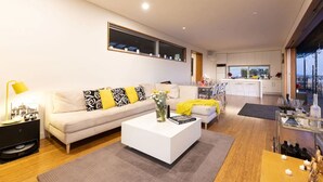 Ein modernes Wohnzimmer mit Sofa, Couchtisch und Essbereich mit Stühlen.