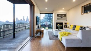 Ein modernes Wohnzimmer mit Blick auf die Stadt, einer Couch, einem Couchtisch und einem Kamin.