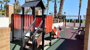 Ein Spielplatz mit einer Kletterkonstruktion, einer Rutsche und einer Bank.
