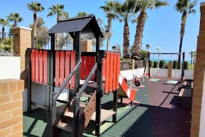 Explore the outdoor play area, featuring a climbing structure surrounded by palm trees.