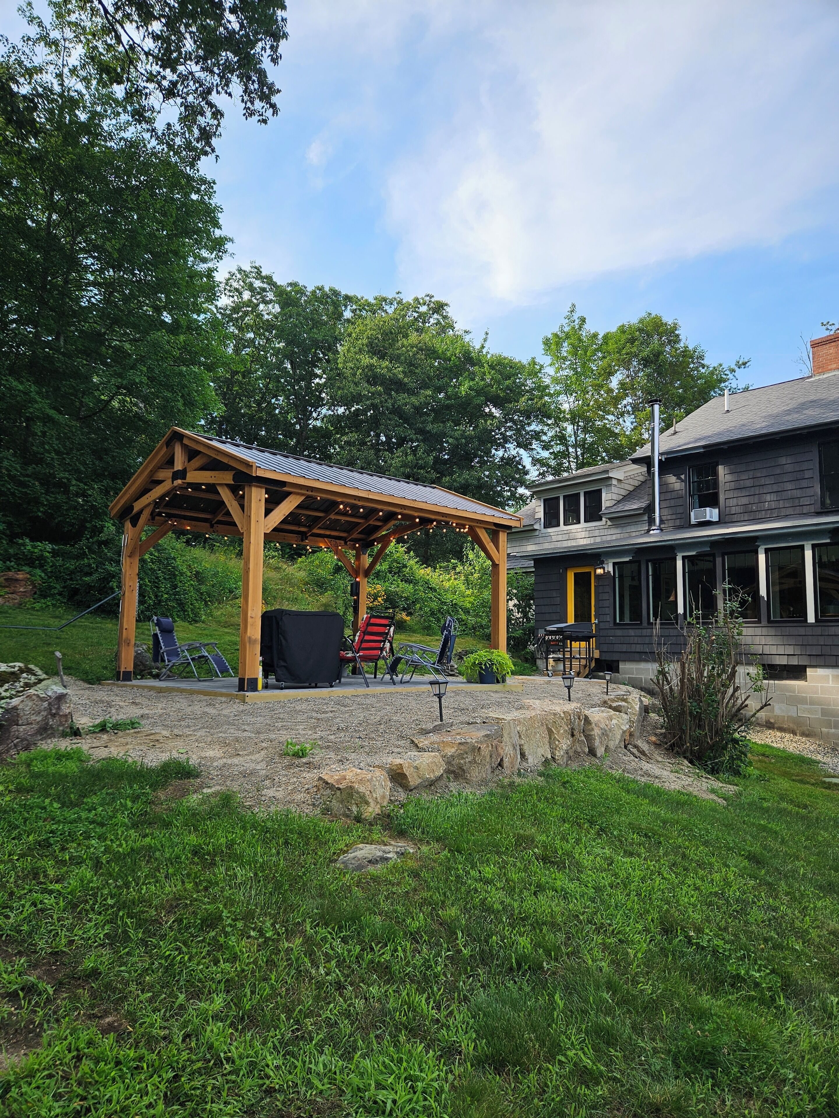Un espace extérieur aménagé avec une zone de sièges couverte, une pergola, un barbecue et une chaise de patio.