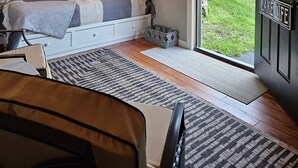 Ett mysigt sovrum med en säng, sänglampor, ett fönster och en dörr med texten ”LIVET VID SJÖN”.
