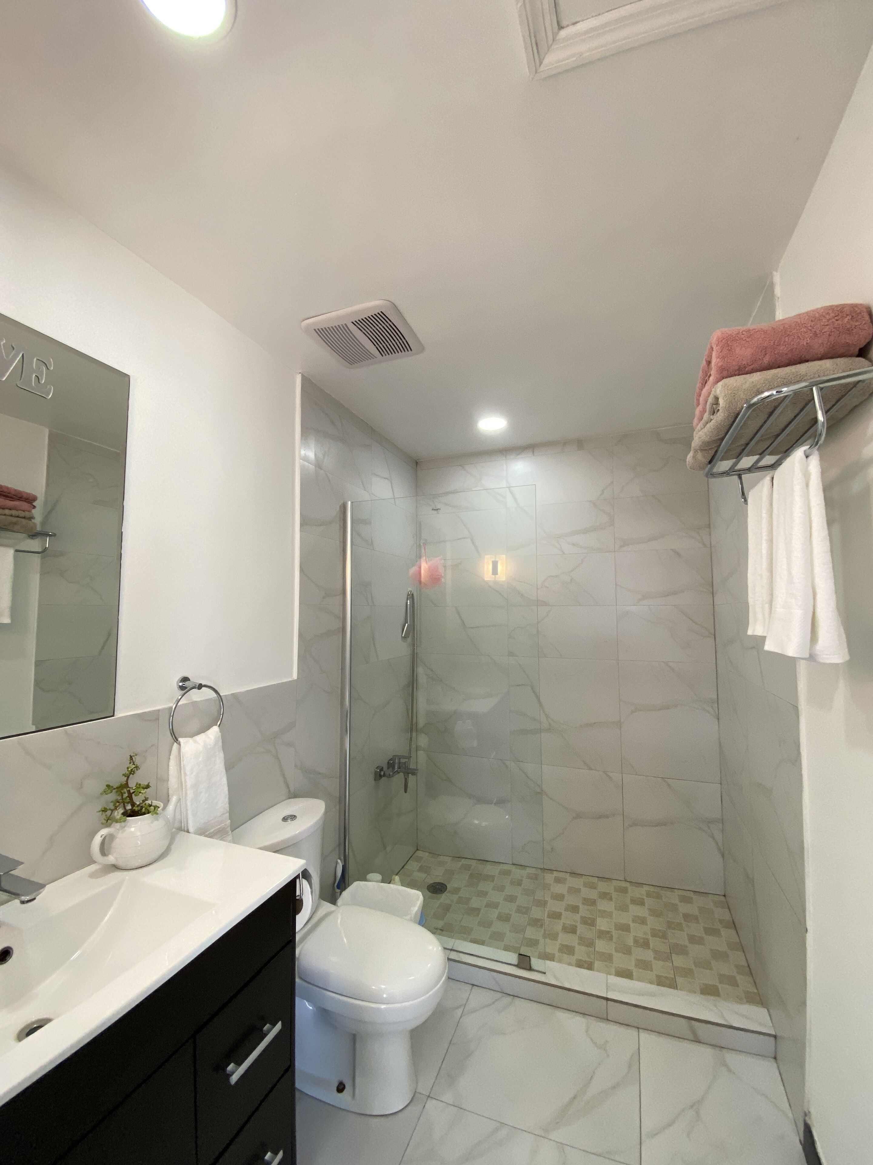 Une salle de bain moderne dotée d’une douche à parois de verre, de toilettes, d’un lavabo et d’un meuble-lavabo avec un miroir.
