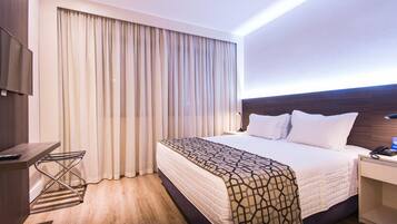 A hotel room with a bed, a desk, a chair, and a TV.