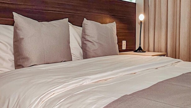 A hotel room with a large bed, a nightstand, a lamp, and a view of the outdoors. - Transamerica Executive Taboão da Serra Morumbi (Taboão da Serra)