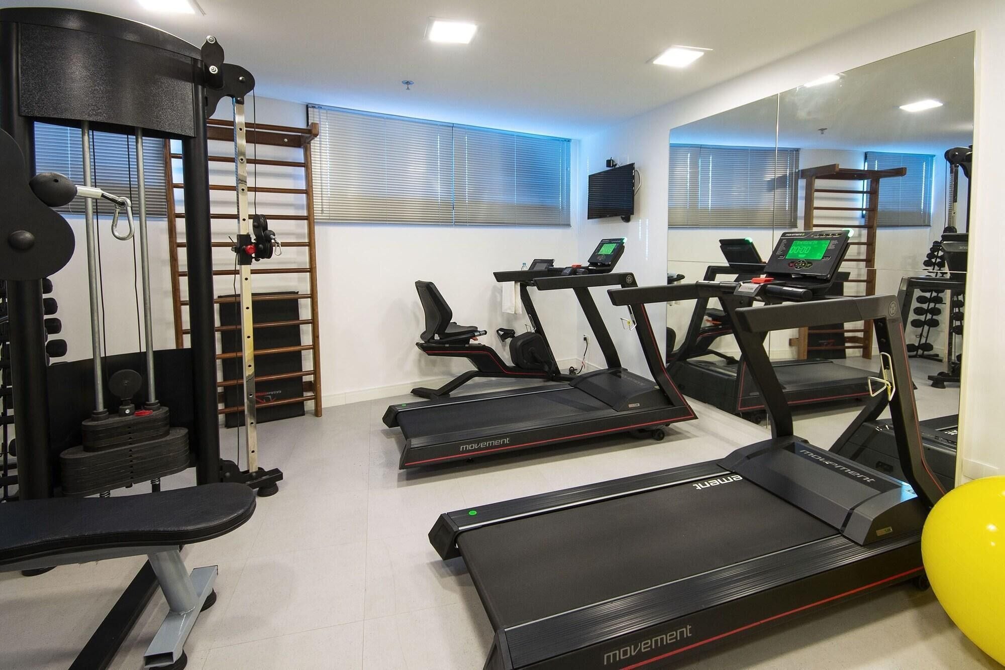 A gym with treadmills, weight machines, and a mirror.