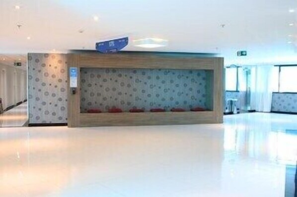 Un área de recepción con diseño moderno, un mostrador de madera y una pared con diseño geométrico.