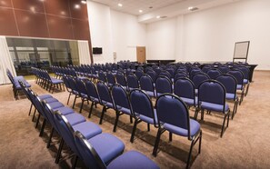 Un salón de conferencias con filas de sillas azules y piso alfombrado.