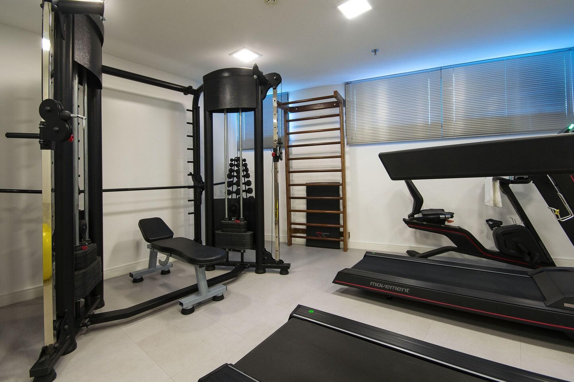 Un gimnasio en casa con una jaula para sentadillas, banco, máquina de poleas, barra de dominadas y una cinta de correr.