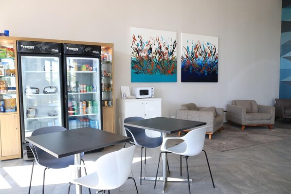 A modern room with a black table, white chairs, a white cabinet, and two abstract paintings on the wall.