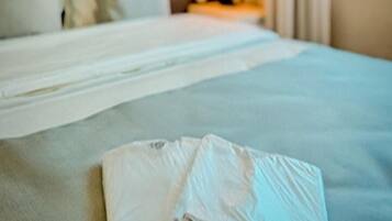 Una habitación de hotel con una cama bien hecha, cabecera y ventana con cortinas.