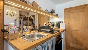 A kitchen with a wooden countertop, stainless steel sink, and a wooden door.
