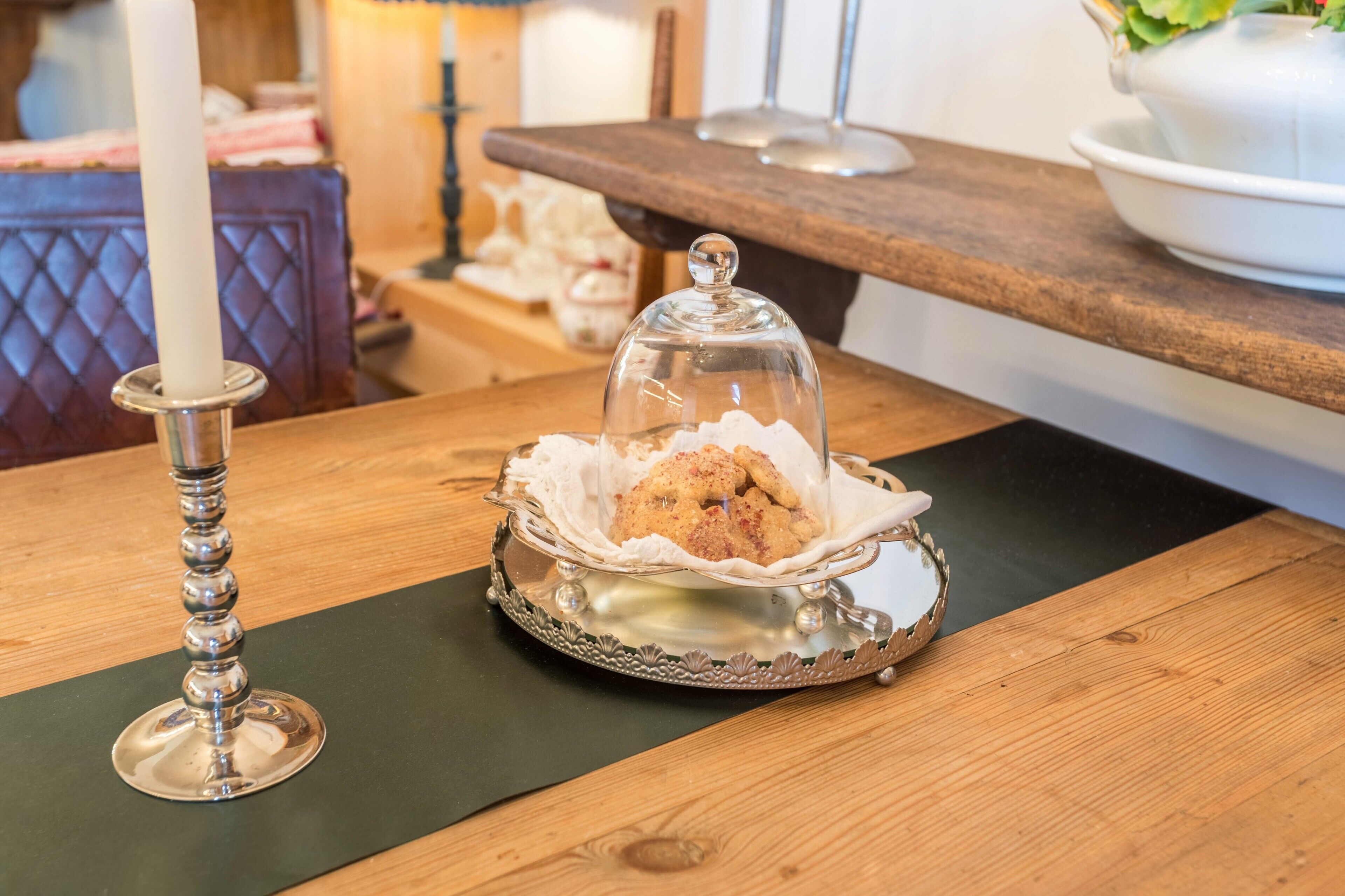 Une table avec un chandelier, un présentoir en verre contenant des biscuits et une surface en bois.