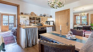 A cozy kitchen with wooden cabinets, a dining table, and a chandelier.