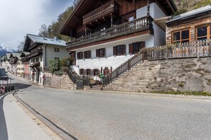 Ein traditionelles Chalet mit Steinstufen, Holzbalkonen und Blick auf einen schneebedeckten Berg.