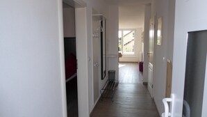 A narrow hallway with a coat rack, a metal rack, and a door leading to a room. - Holiday Apartment "Domicilio Azzurro" with Lake View and Wi-Fi (Lindau am Bodensee)