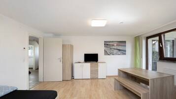 Ein modernes Zimmer mit einem Bett, einem Fernseher auf einer Kommode, einer Holzbank und einem Fenster.