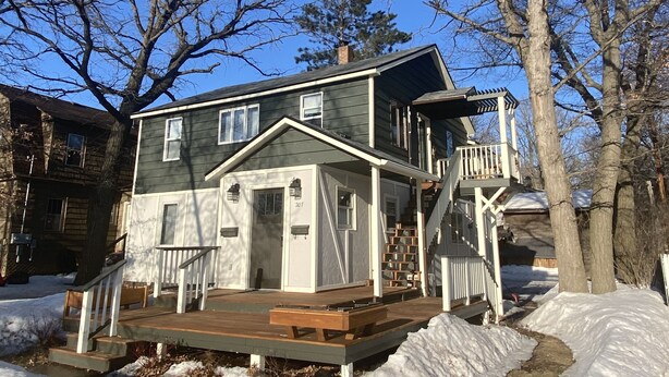 A two-story house with a front deck and a covered porch.