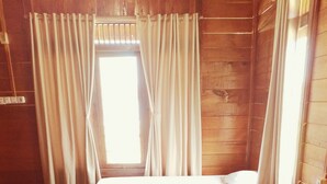 Une chambre avec deux lits, des murs en bois et une fenêtre avec des rideaux.