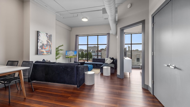 A modern office space with a dining area, black sofas, and large windows offering city views.