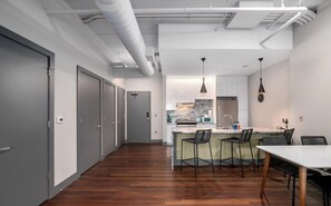 A modern kitchen with a central island, bar stools, and pendant lighting.
