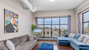 Una sala de estar moderna con un sofá gris, un sofá modular azul y un ventanal con vistas a la ciudad.