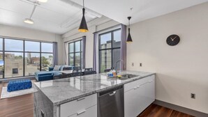 Una cocina moderna con una isla grande, lavavajillas integrado e iluminación colgante.