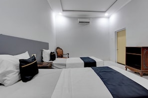 Habitación de hotel con dos camas, una silla, aire acondicionado y un armario.