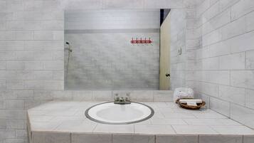 Un baño con una bañera grande, un lavamanos y una ducha.