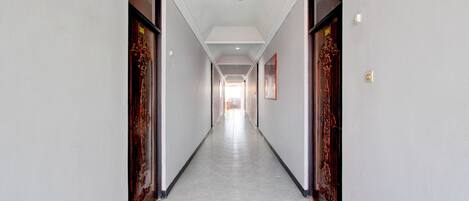 A long, narrow hallway with doors on both sides, a tiled floor, and a red carpet at the end.