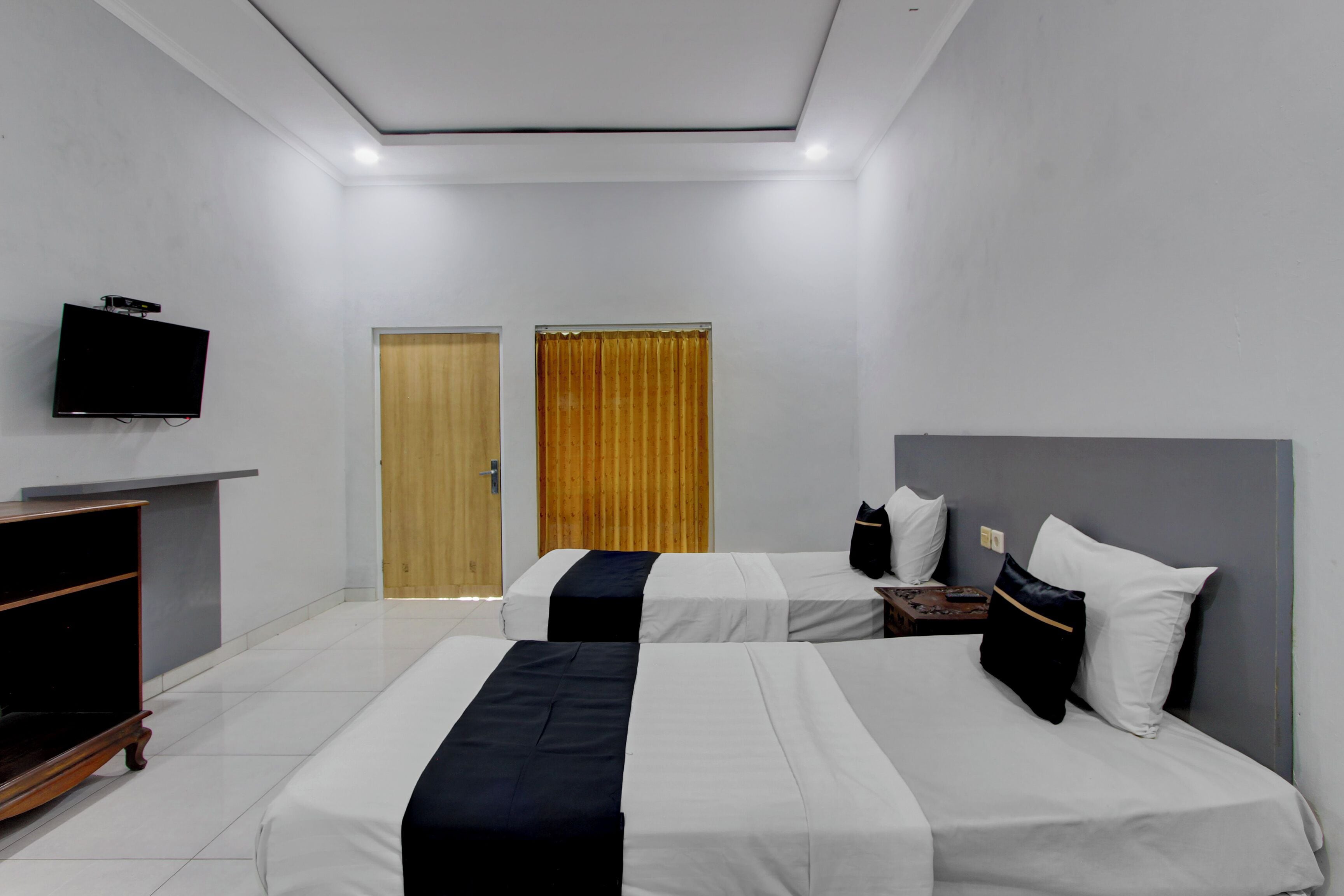 Habitación de hotel con dos camas, un televisor y una puerta de madera.