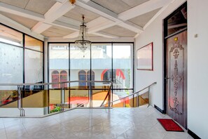 Un interior espacioso con techos altos, una araña de cristal, una escalera y ventanas grandes que ofrecen vistas al exterior.
