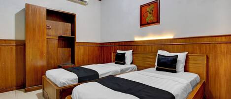 Quarto de hotel com duas camas, um guarda-roupa, ar condicionado e uma obra de arte pendurada na parede.
