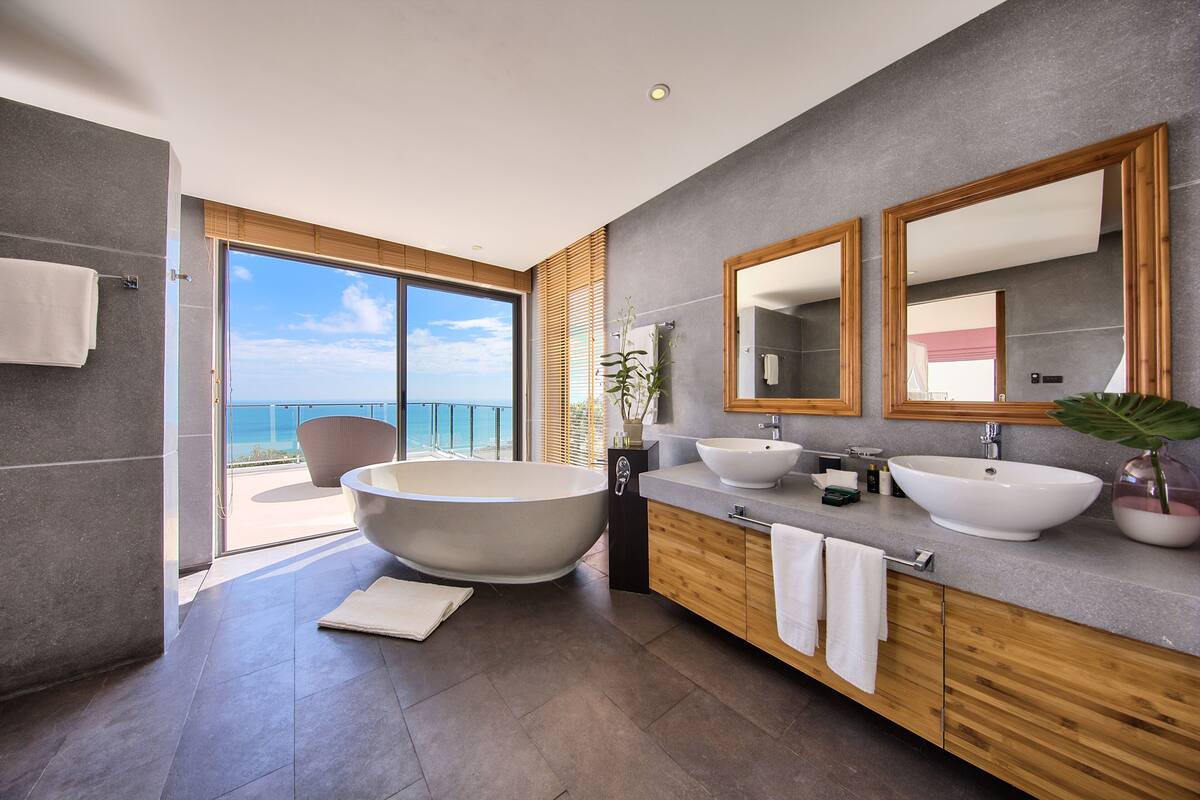 A modern bathroom with a large bathtub, two sinks, and a large mirror.