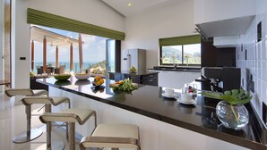 Eine moderne Küche mit einer großen Kochinsel, Barhocker und Blick aufs Meer.