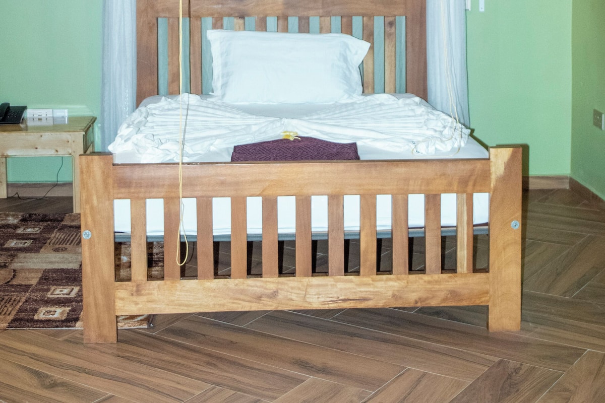 A wooden bed with a canopy, a bedside table, and a patterned rug.