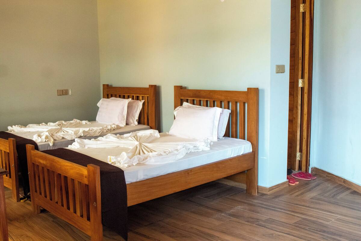 A room with two wooden beds, a wooden bench, and a wooden door.